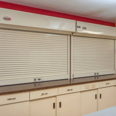 Two beige roll-up security shutters closed over a counter in a room with red walls.